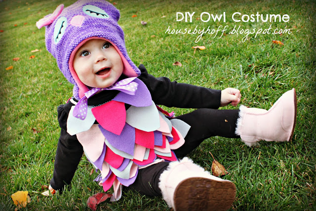 Little girl sitting i grass in owl costume