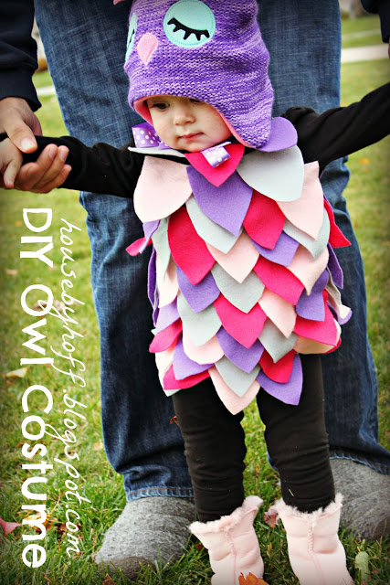 Little girl standing in the owl costume.