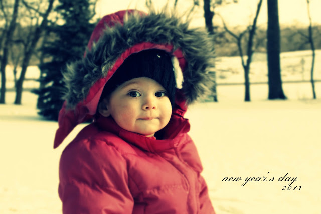 Little girl in a red jacket sitting in the snow.