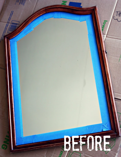 The mirror before being painted a dark brown with blue painters tape around it.