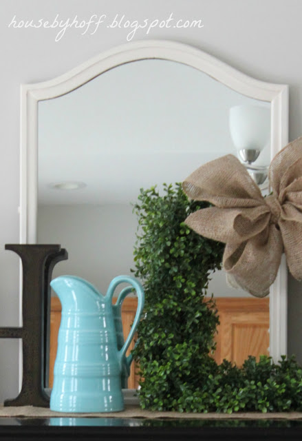 The mirror painted a white color with a small fresh green wreath and burlap bow in front of it.