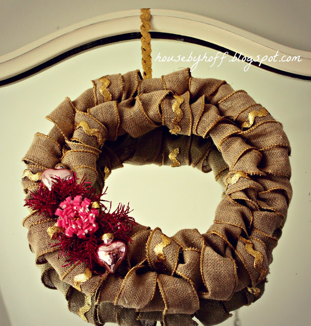 A burlap wreath hanging in front of a mirror.