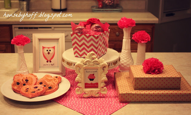 Red flowers in white vases, breakfast toast and presents on the table.