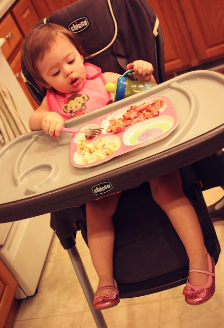 Little girl eating her breakfast at her high chair.