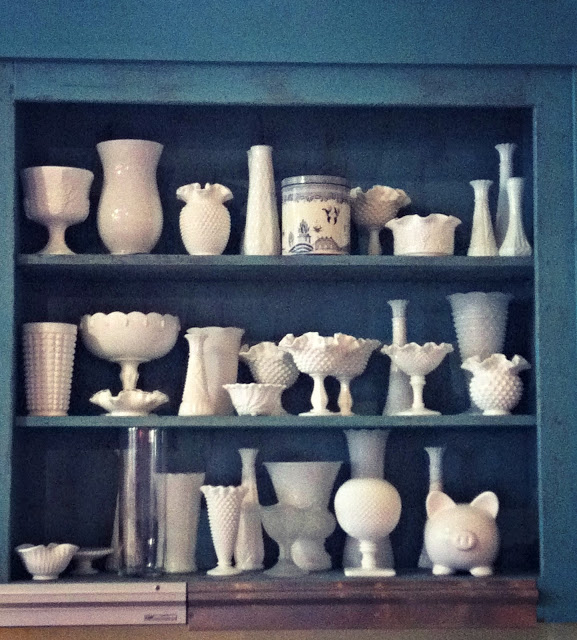 A shelf containing all different sizes and types of white pottery.