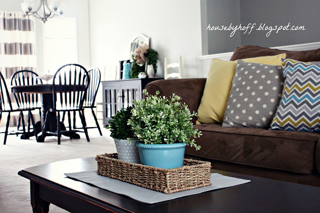 A coffee table in front of a couch with the pillows on the couch.