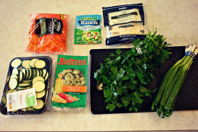 Carrot, cucumber, parmesan, tortellini, chives on counter.