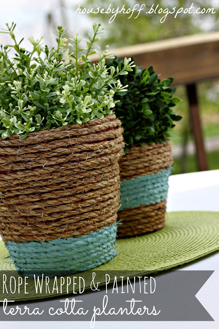 Terra cotta pots with decorative rope wrapped around and green plants in them.