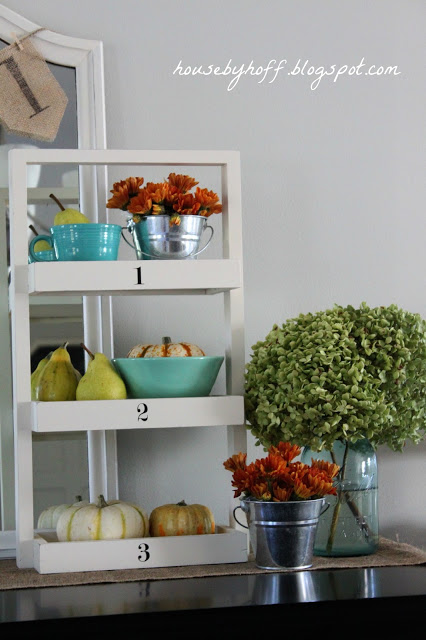 White shelf with flowers, and pumpkins on it.