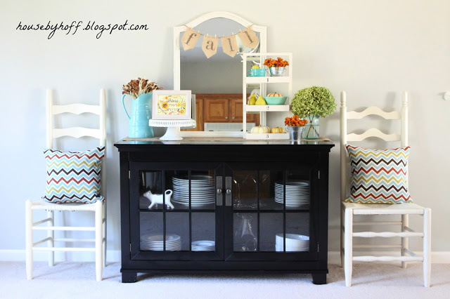 Two chairs beside the china cabinet with throw pillows on them.