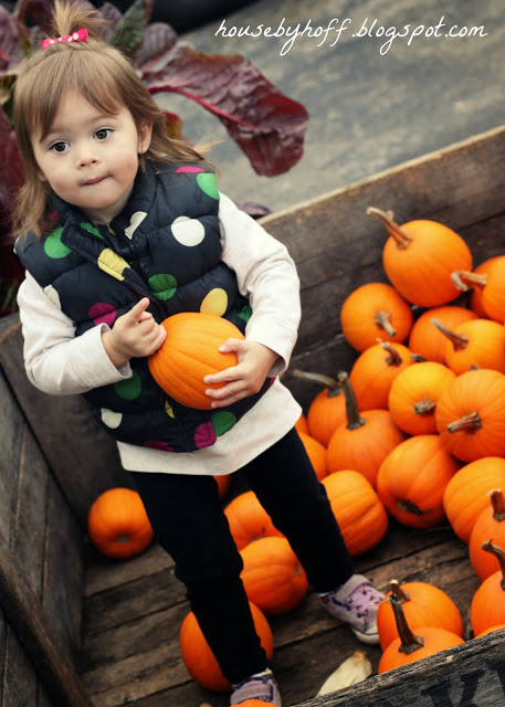 Little girl carrying a pumpkin.