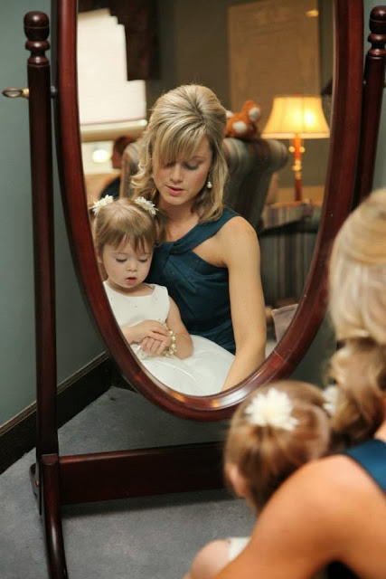 Mom holding a child looking into the mirror refelection.