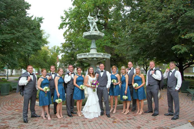 The wedding party standing in front of a fountain.