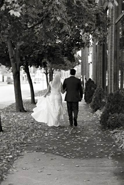 The just married couple walking down the sidewalk.