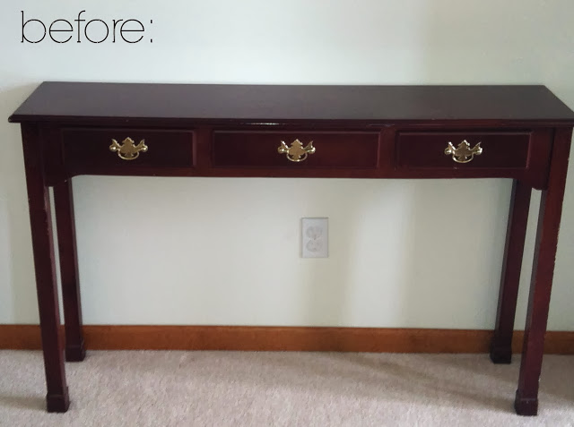 An old console table beside a white wall.