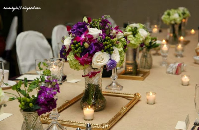 Floral bouquet on the table with candles and a gold frame around the centrepiece.