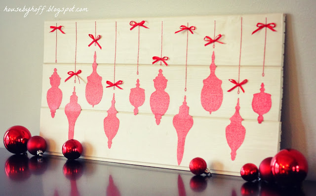 Sparkly ornament cut outs on a board with red bows.