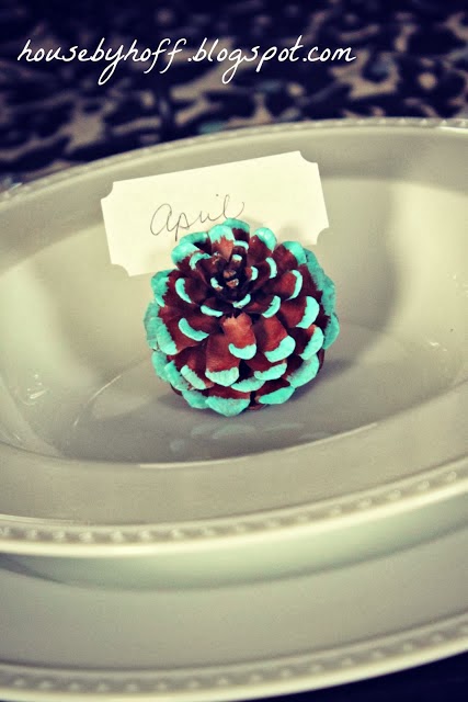 The pine cone with tips painted blue and on the table as a card holder.