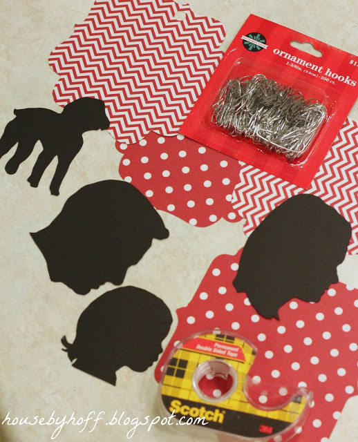 Silhouettes of people and an animal on the counter with tape and ornament hooks.