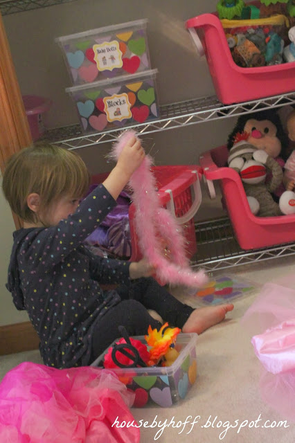 Little girl playing with pink fluffy feather boa.