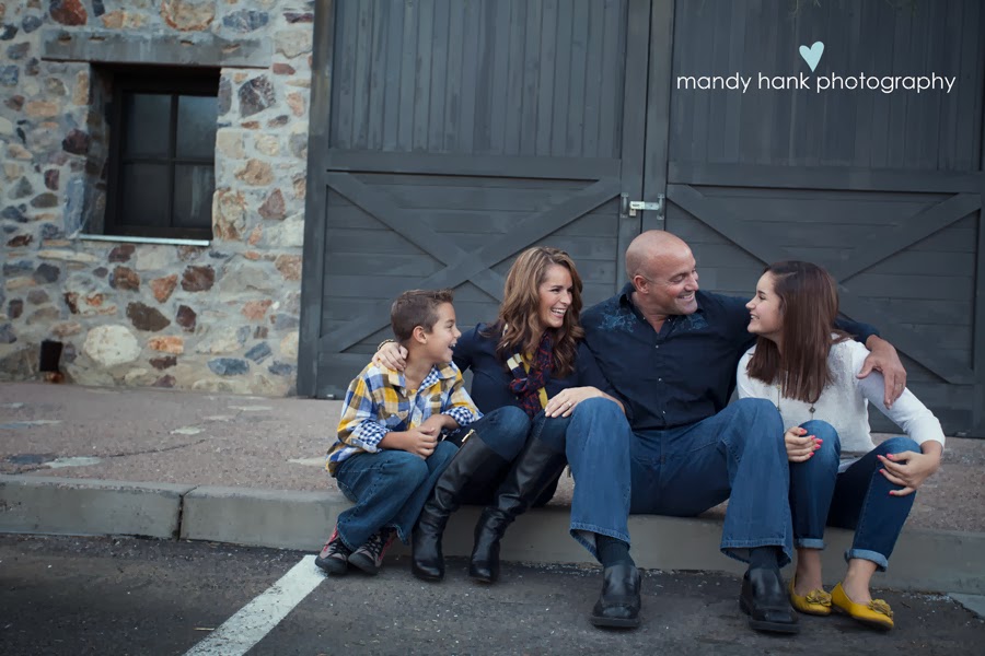 A family of four in front of a barn like door.