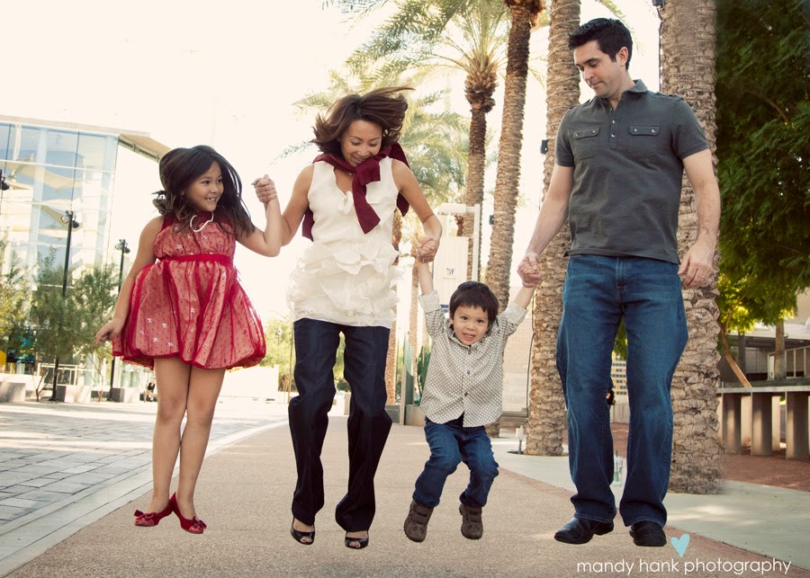 A Dad, Mom and two kids walking down the street holding hands.