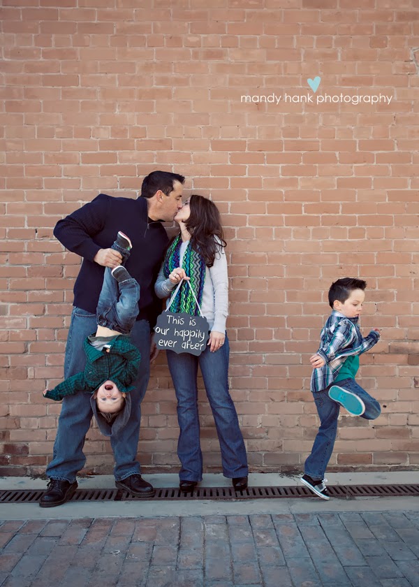 tips for family photos via housebyhoff.com Mom and Dad kissing against a brick wall with the Dad holding a child upside down.