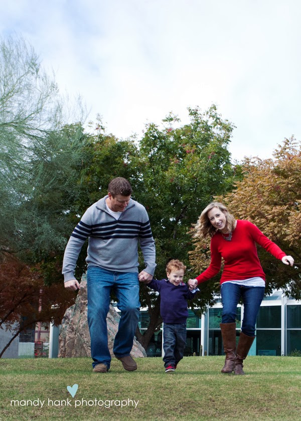 Mom Dad and child skipping in the grass.