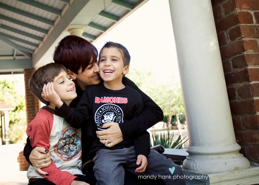 A Mom and her kids outside a residence and she is snuggling them.