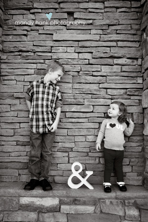 A brother and sister standing against a stone wall.