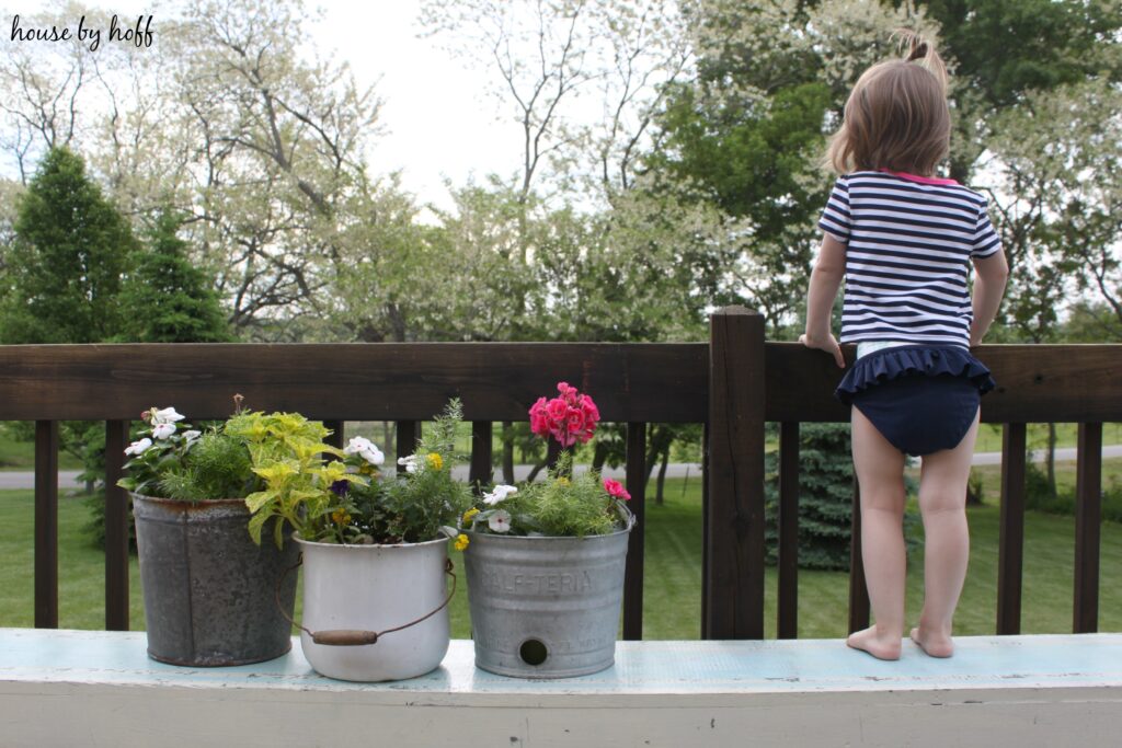 Little girl standing on bench looking over a railing.