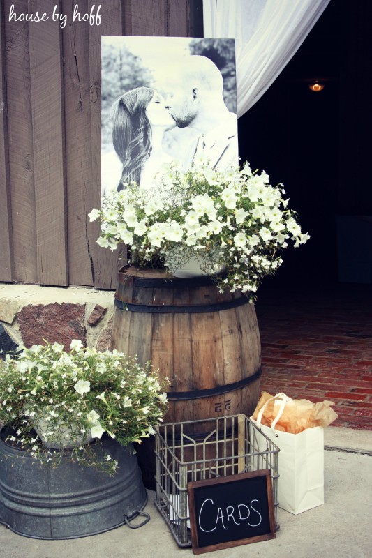 Wooden Barrel with flowers and a picture of the couple kissing behind it.