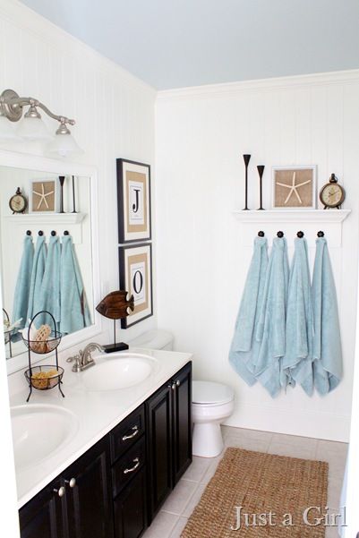 Small bathroom with blue towels and seashell picture on the wall.