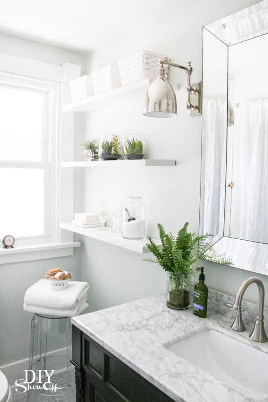 All white bathroom with green plants and chrome lights.