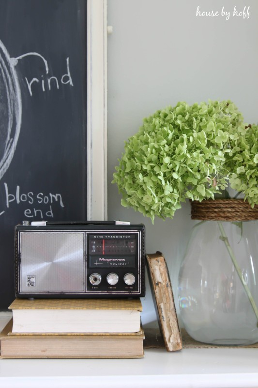 Vintage radio sitting on books on shelf.