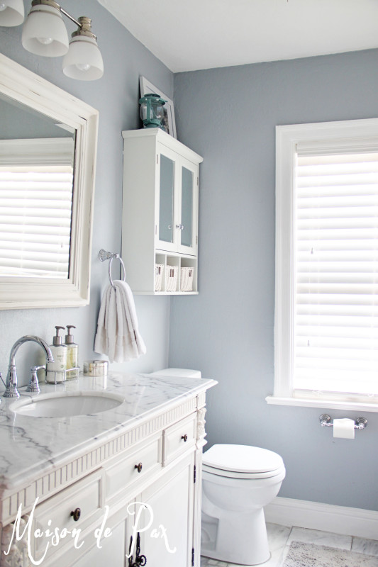 Soft blue walls in a all white bathroom.