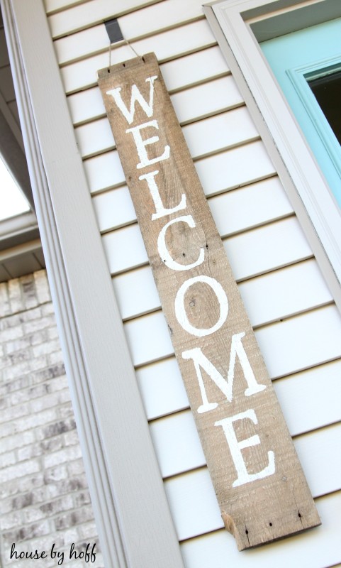 The word welcome on a wooden sign hanging by the doorway.