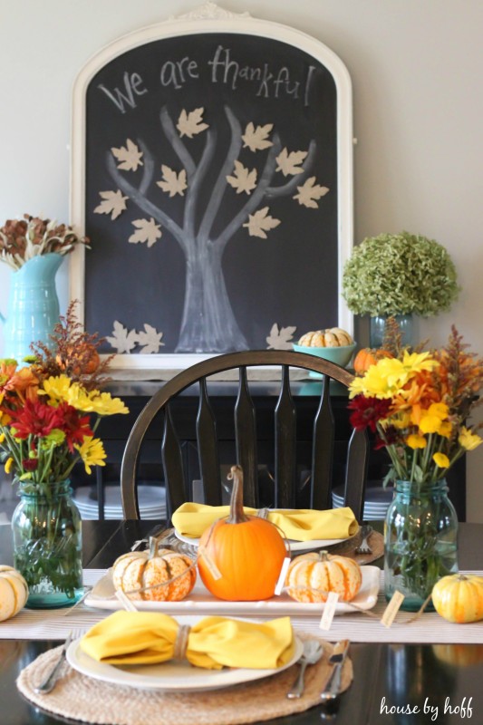 Chalkboard in dining room with we are thankful written on it with a tree and leaves on it to.