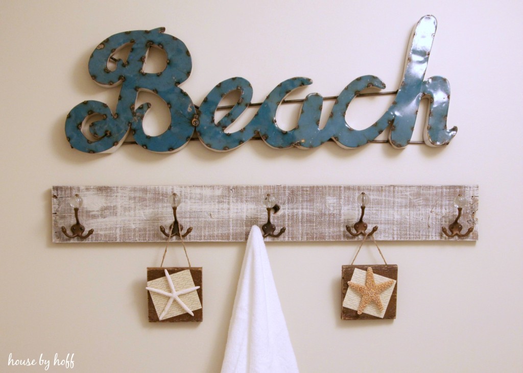 Blue beach sign and towel rack hanging below it.