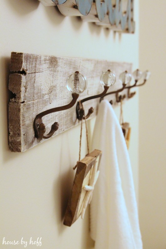The wood towel rack with vintage hooks and a towel hanging on it.