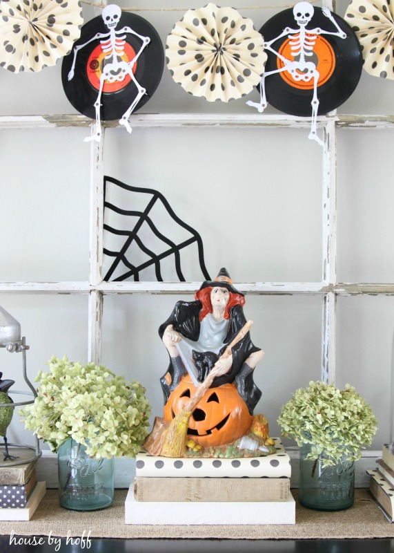 Skeleton garland above a witch with a broom and hydrangeas.