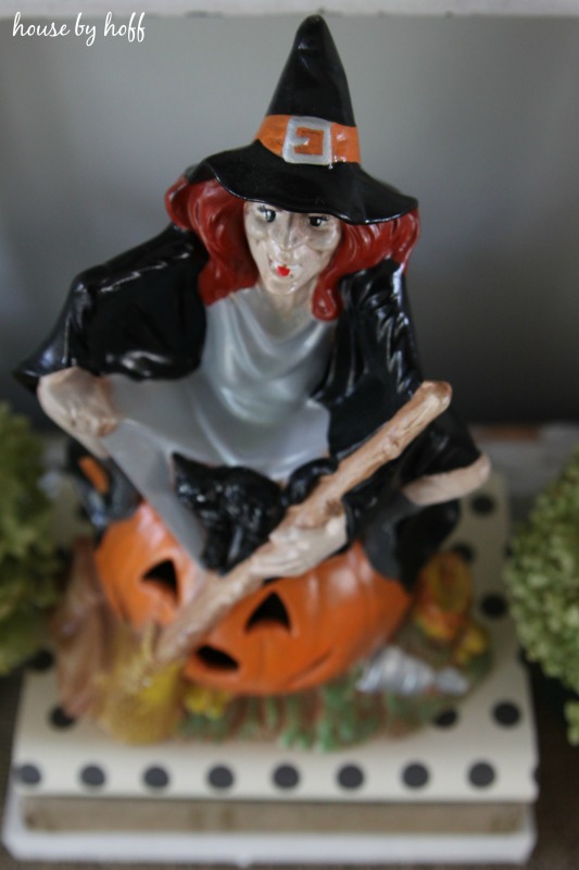 Up close picture of the witch with red hair sitting on a pumpkin.