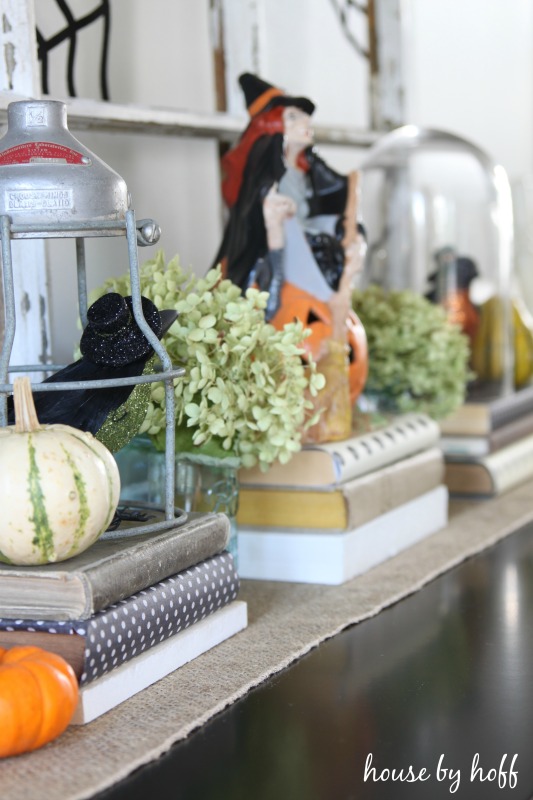 Books stacked up on the shelf with pumpkins and a witch on them.