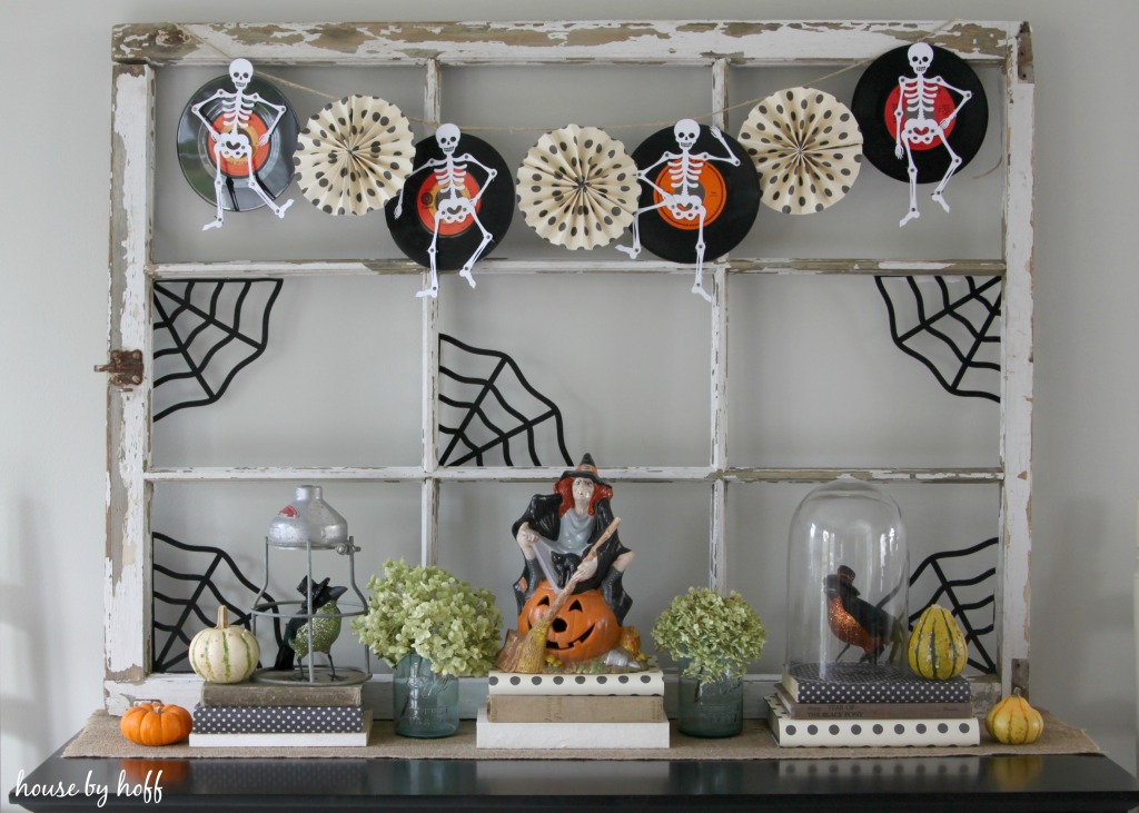 An old window frame with vintage records, skeletons, cobwebs and pumpkins on it.