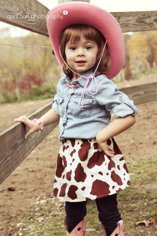 Little girl with a pink cowboy hat and cowgirl skirt on in picture.