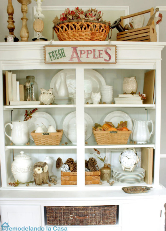 White hutch decorated for fall with red and orange and green.