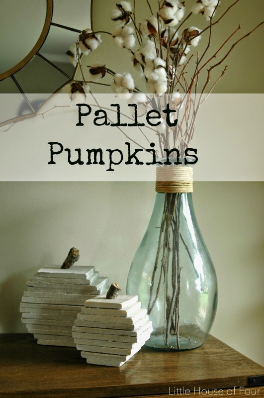 Desk with pallet pumpkins and a clear vase with twigs.