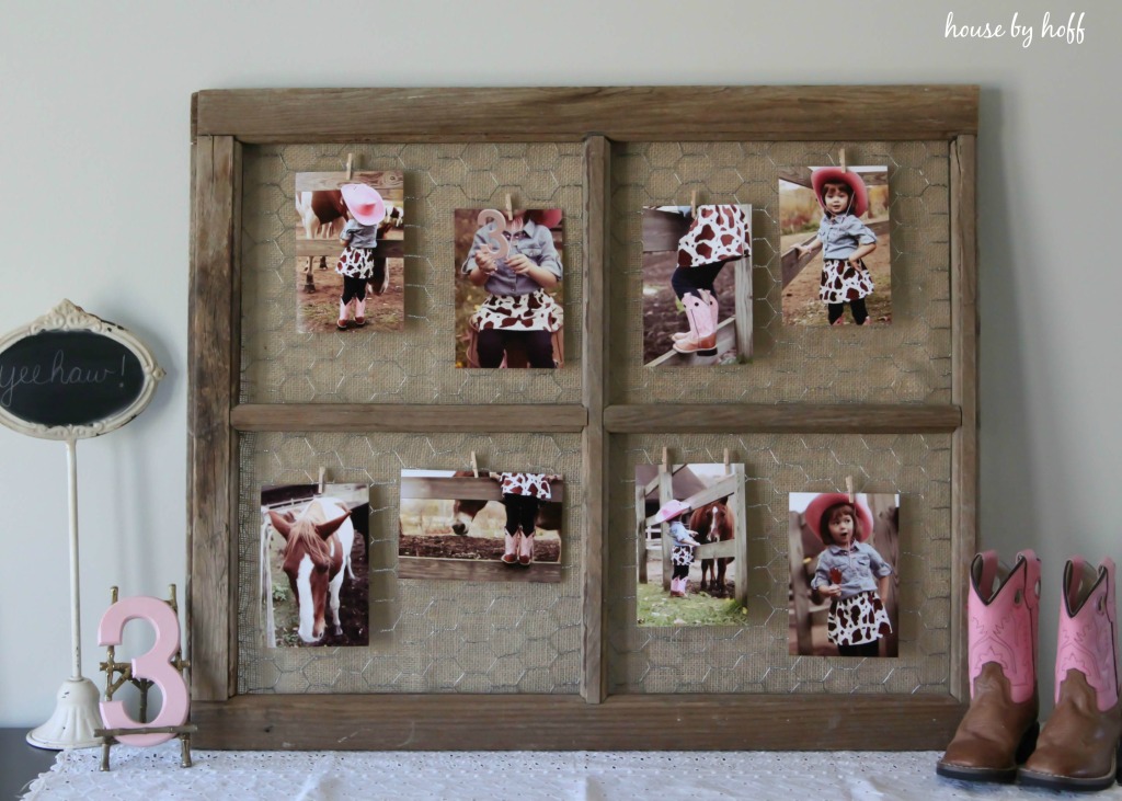 Large old window with chicken wire and photos hanging on it.