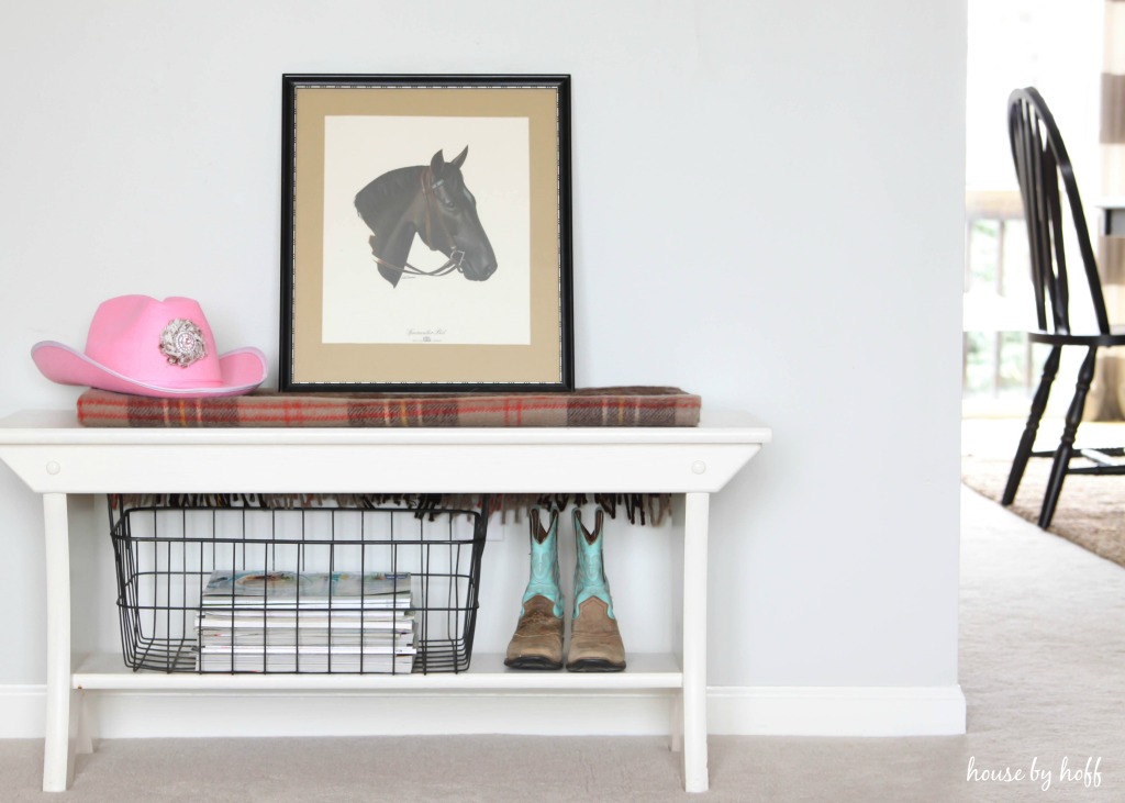 Pink cowboy hat and horse framed picture on table.