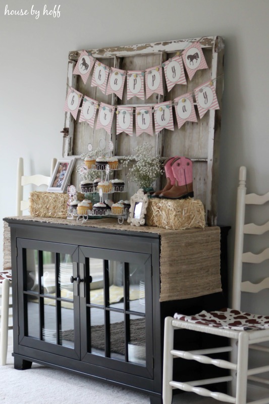 Cupcakes, cowgirl boots and hay bales on side table.